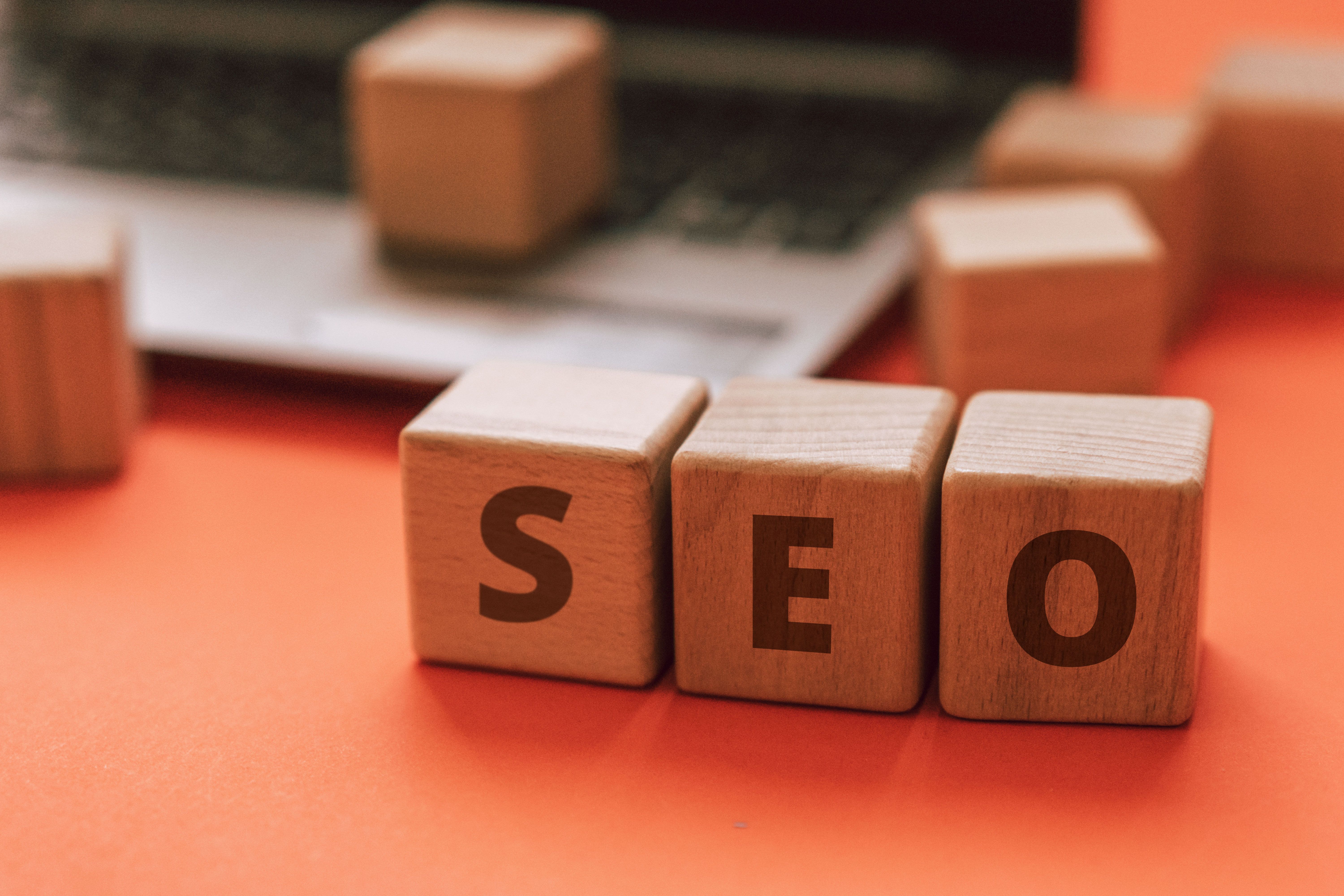 SEO letters on wooden blocks with a laptop in the background
