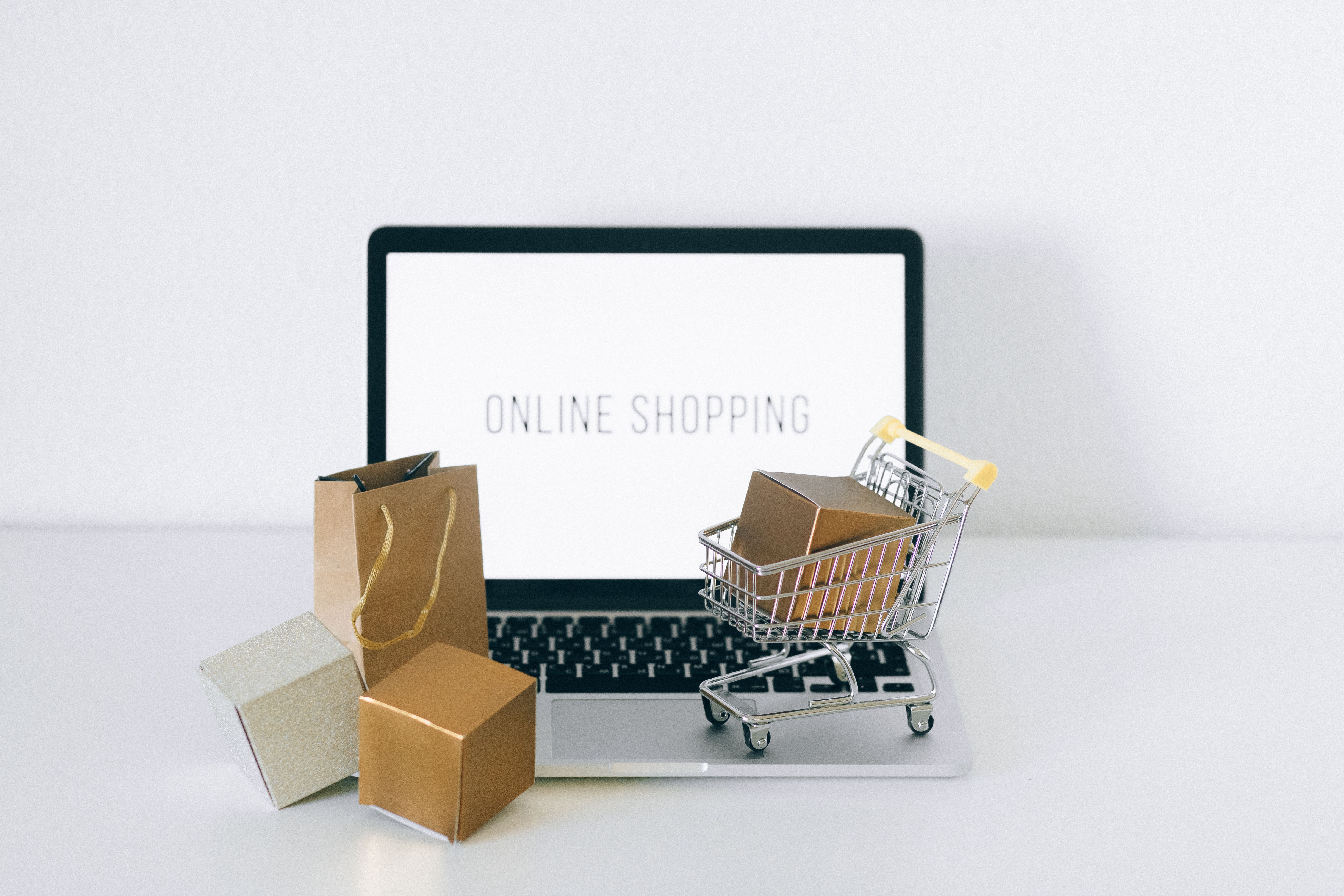 Laptop with online shopping display, boxes and shopping cart